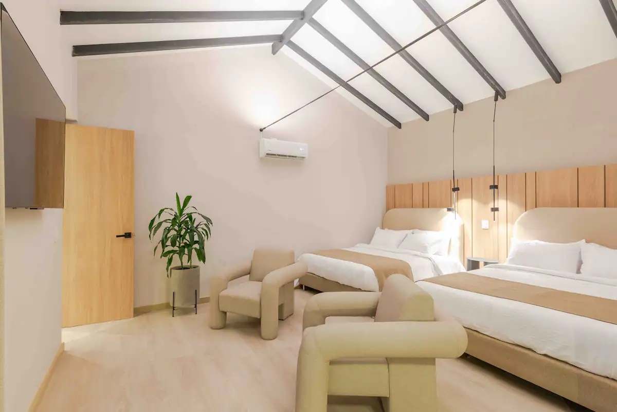 Habitación principal amplia con dos camas, sillones y luz natural en apartamento del Hotel Lincoln